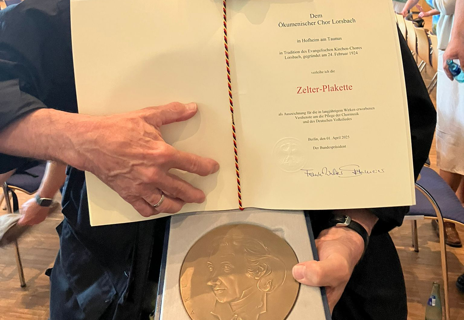 Ulrich Stoll hält die Urkunde und die Zelter-Plakette des Ökumenischen Chors Lorsbach in den Händen.
